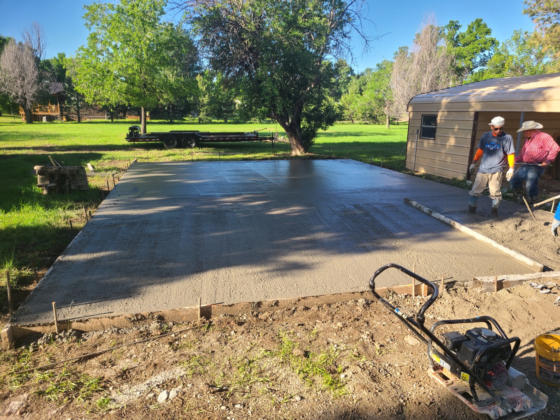 Completed concrete slab next to a metal carport